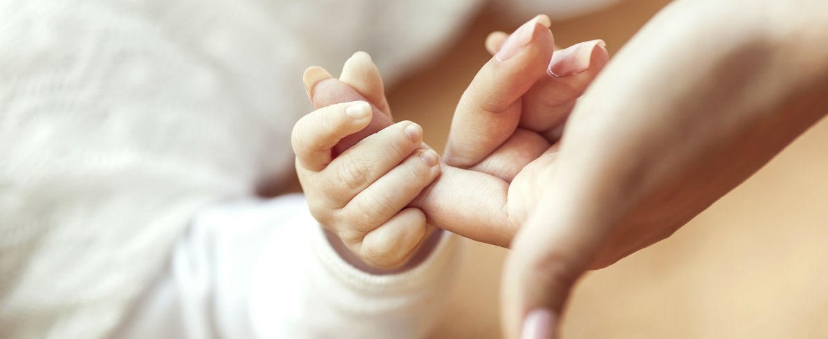 A new born holding an adult’s finger